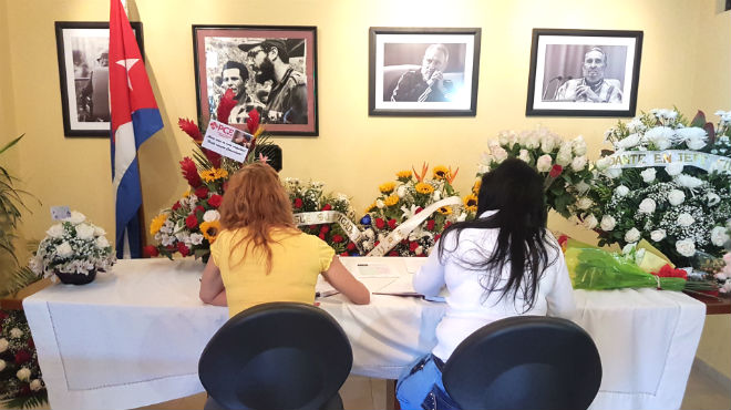Asistentes escriben sus condolencias en el libro para Fidel Castro.